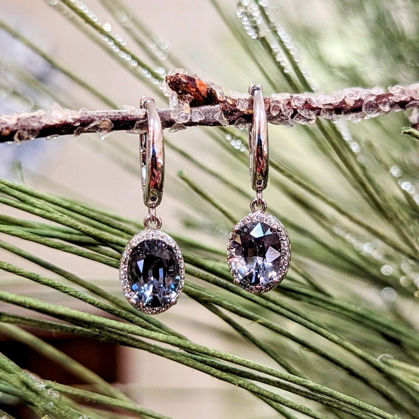 Photo of Grey Spinel Halo Dangle Earrings in a decorative scene, designed by , available at Plumb Gold & Plumb Silver