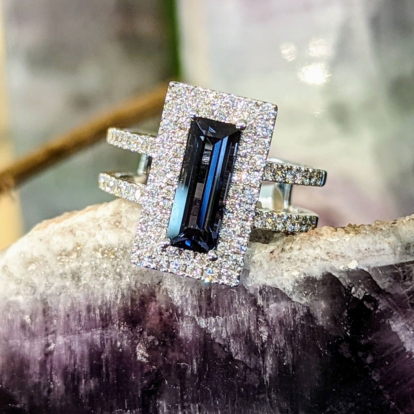 Photo of Grey Spinel Halo Split Shank Ring in a decorative scene, designed by , available at Plumb Gold & Plumb Silver