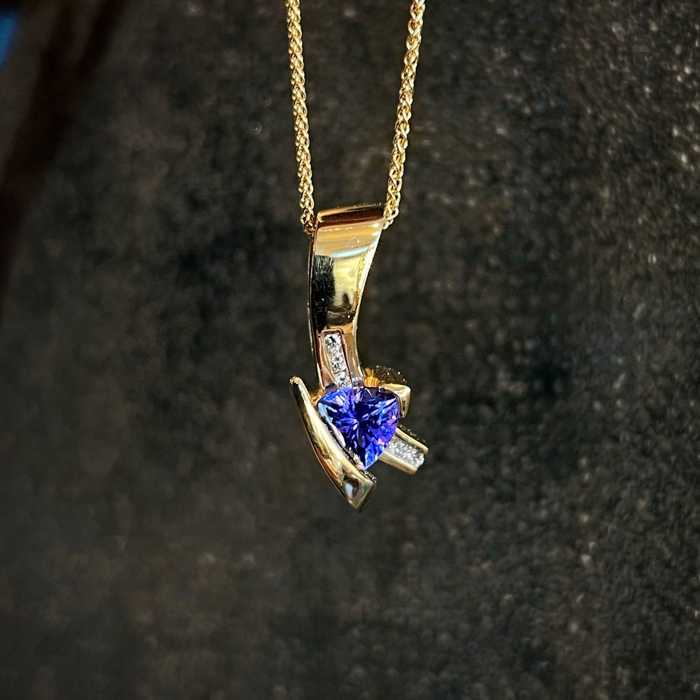 Photo of HL Tanzanite and Diamond Pendant in a decorative scene, designed by , available at Plumb Gold & Plumb Silver