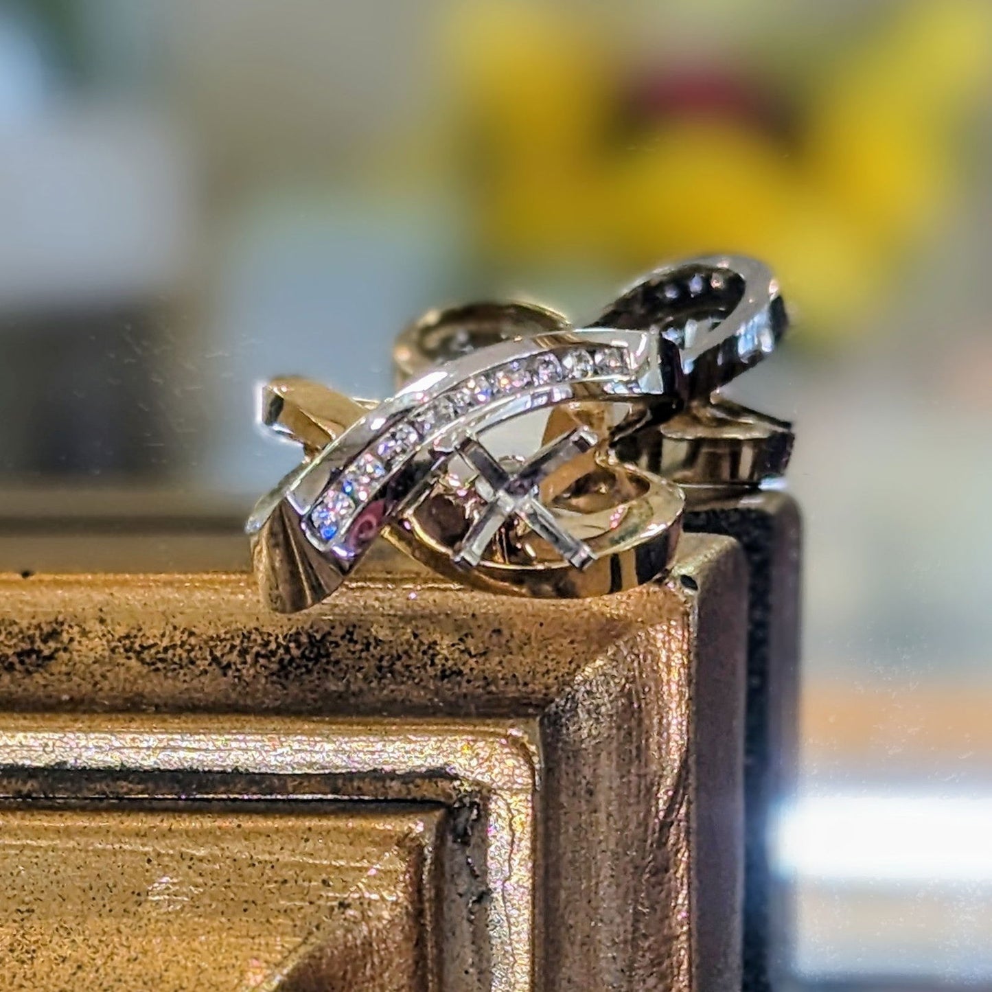 Photo of H L Crossover Ring Mounting in a decorative scene, designed by , available at Plumb Gold & Plumb Silver