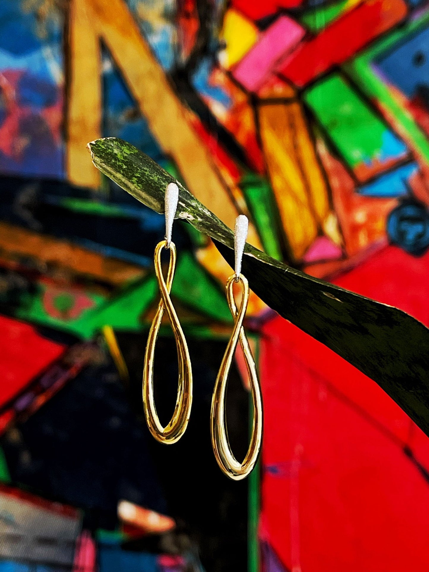 Photo of "Infinity" Dangle Earrings in a decorative scene, designed by , available at Plumb Gold & Plumb Silver