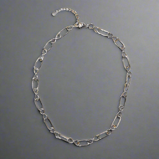 Photo of Infinity Link Chain in a decorative scene, designed by , available at Plumb Gold & Plumb Silver