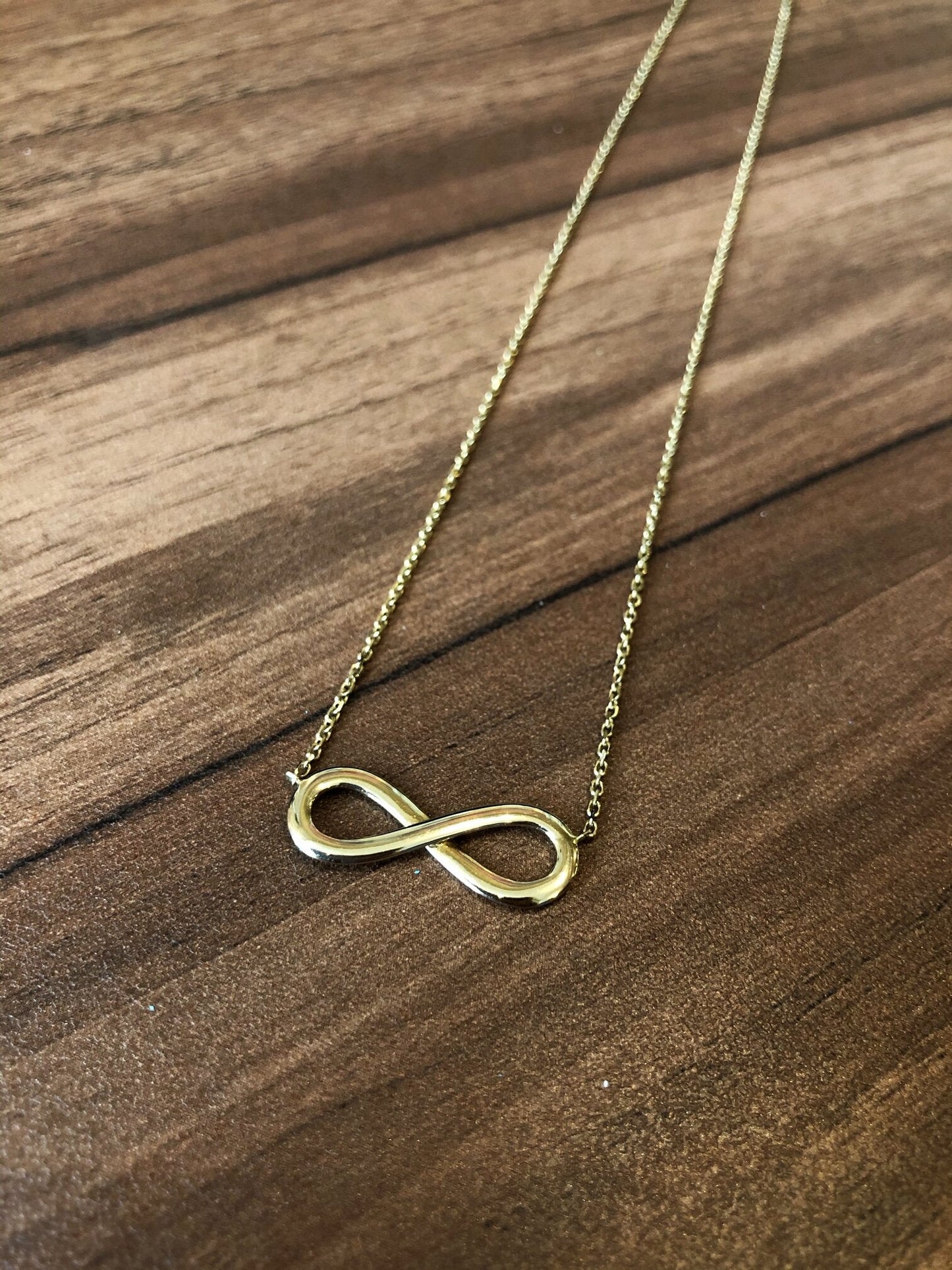 Photo of Infinity Necklace in a decorative scene, designed by , available at Plumb Gold & Plumb Silver