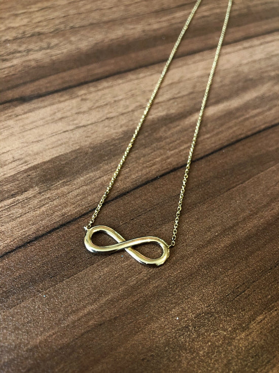 Photo of Infinity Necklace in a decorative scene, designed by , available at Plumb Gold & Plumb Silver