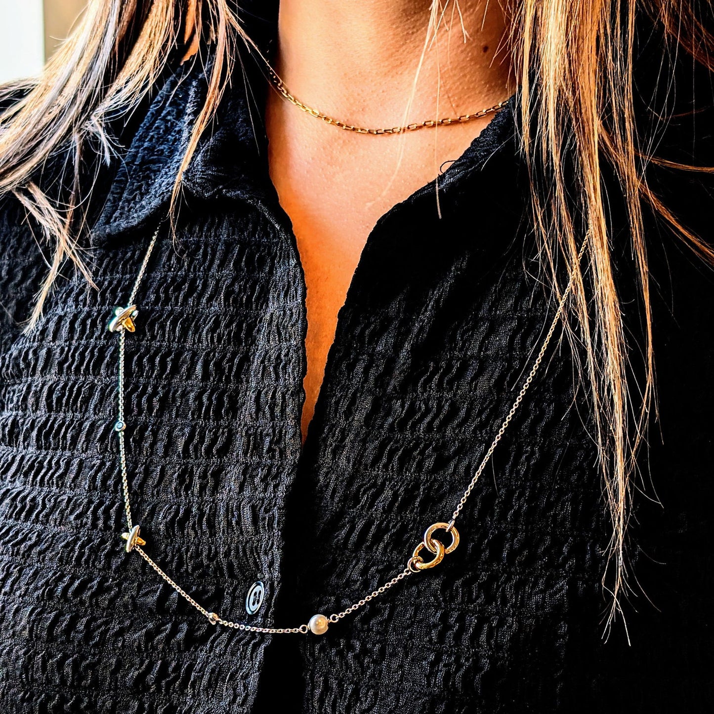 Photo of Intertwined Circle & Cross Station Necklace in a decorative scene, designed by -, available at Plumb Gold & Plumb Silver