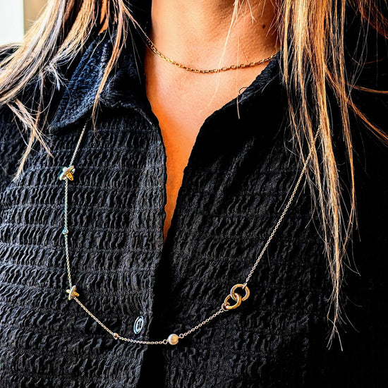 Photo of Intertwined Circle & Cross Station Necklace in a decorative scene, designed by -, available at Plumb Gold & Plumb Silver
