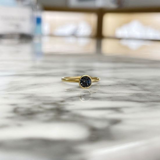 Photo of Kim Collins Grey Spinel Ring in a decorative scene, designed by , available at Plumb Gold & Plumb Silver