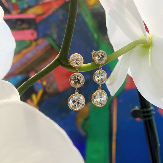 Photo of Kimberly Collins Champagne Zircon Triple Drop Earring in a decorative scene, designed by , available at Plumb Gold & Plumb Silver