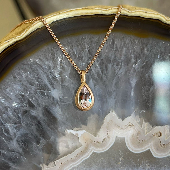 Photo of Kimberly Collins Morganite Pendant in a decorative scene, designed by , available at Plumb Gold & Plumb Silver