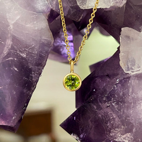 Photo of Kimberly Collins Peridot Pendant in a decorative scene, designed by , available at Plumb Gold & Plumb Silver