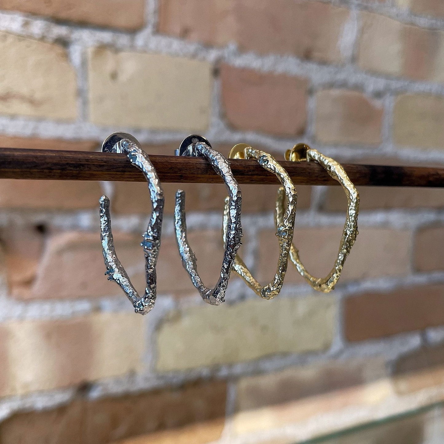 Photo of “Lava” Blue Topaz Hoops in a decorative scene, designed by , available at Plumb Gold & Plumb Silver