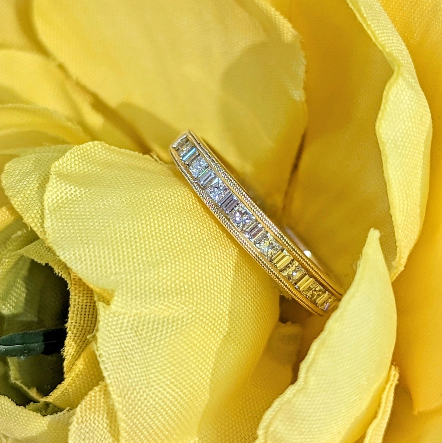 Photo of "Lillian" Princess and Baguette Accented Band in a decorative scene, designed by , available at Plumb Gold & Plumb Silver