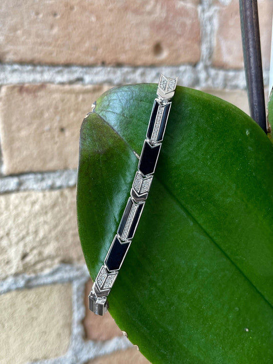 Photo of Linear Arrow Bracelet in a decorative scene, designed by , available at Plumb Gold & Plumb Silver