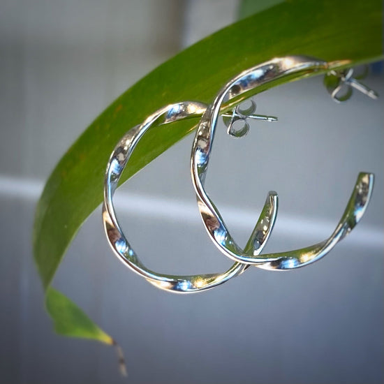 Photo of "Love Twist" Hoops in a decorative scene, designed by -, available at Plumb Gold & Plumb Silver