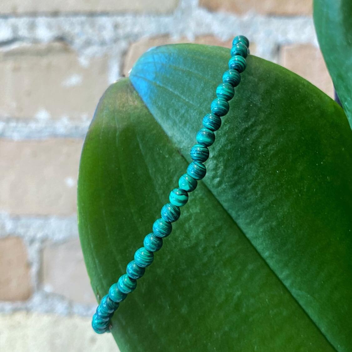 Photo of Malachite Beaded Bracelet in a decorative scene, designed by , available at Plumb Gold & Plumb Silver