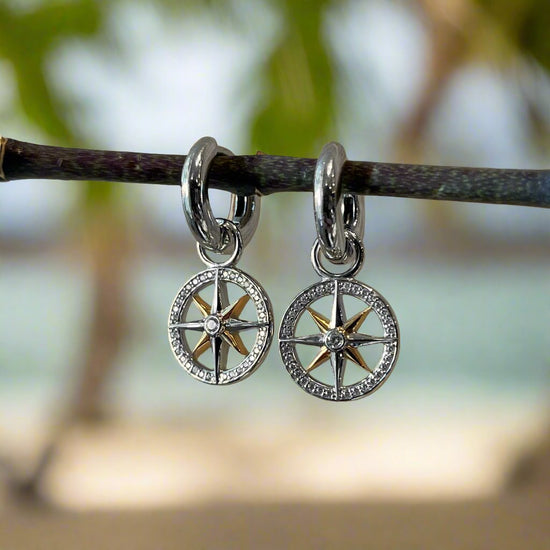 Photo of Mini Compass Earring Charm Set in a decorative scene, designed by , available at Plumb Gold & Plumb Silver