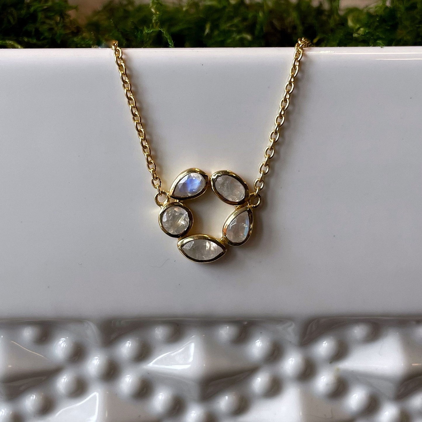 Photo of “Morning” Moonstone Necklace in a decorative scene, designed by , available at Plumb Gold & Plumb Silver