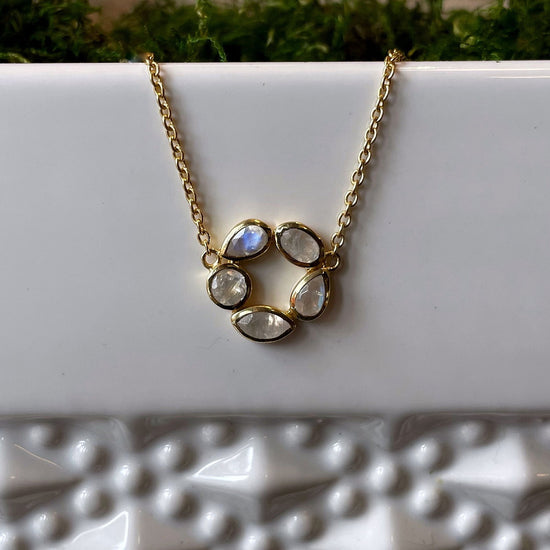 Photo of “Morning” Moonstone Necklace in a decorative scene, designed by , available at Plumb Gold & Plumb Silver