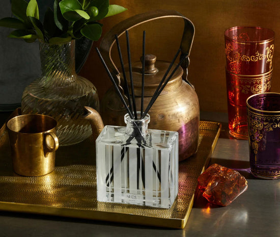 Photo of Moroccan Amber Reed Diffuser in a decorative scene, designed by , available at Plumb Gold & Plumb Silver