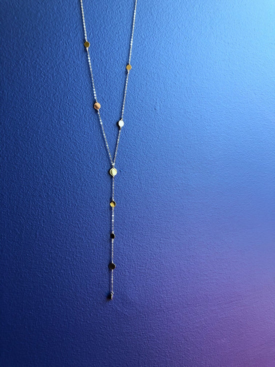 Photo of Multi Disc Y-Necklace in a decorative scene, designed by , available at Plumb Gold & Plumb Silver