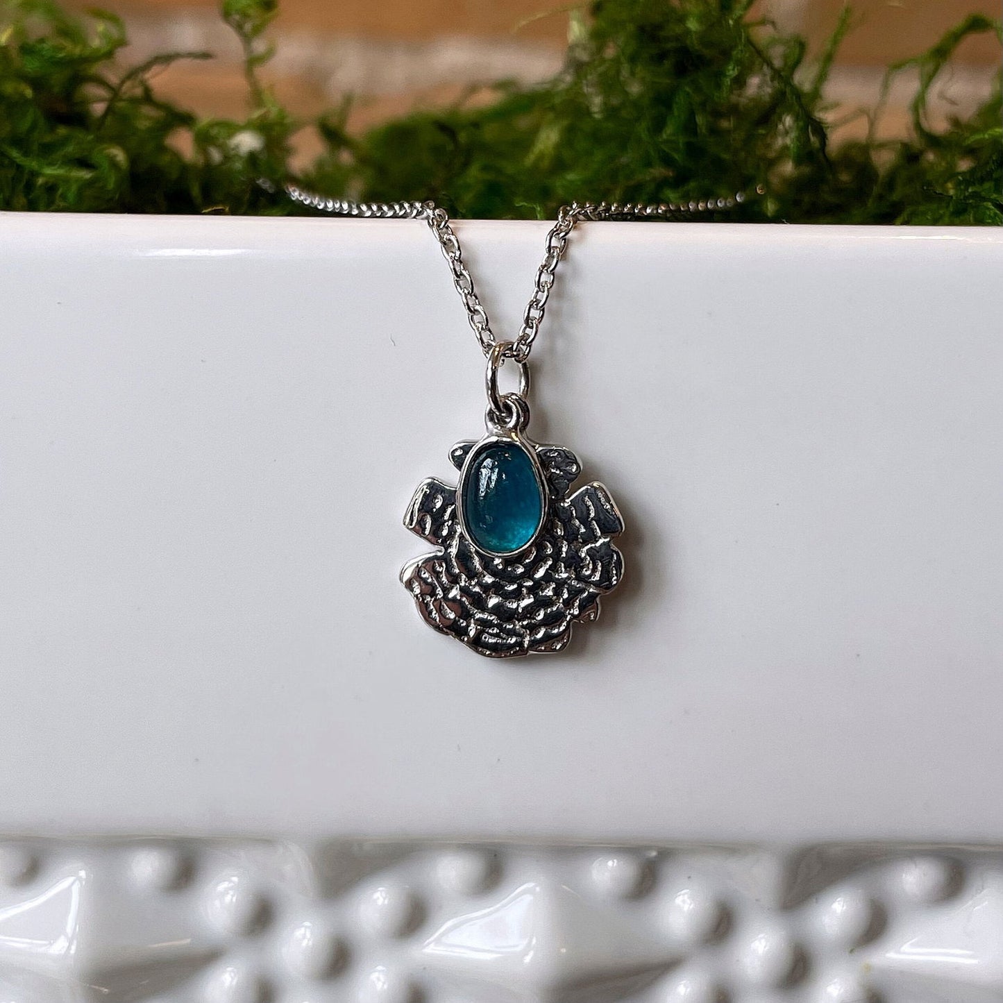 Photo of “Oak” Apatite Necklace in a decorative scene, designed by , available at Plumb Gold & Plumb Silver
