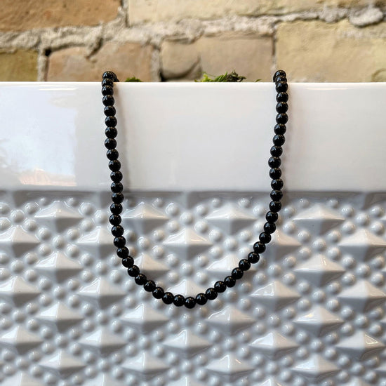 Photo of Onyx Necklace in a decorative scene, designed by , available at Plumb Gold & Plumb Silver