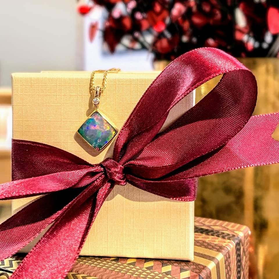 Photo of Opal and Diamond Pendant in a decorative scene, designed by , available at Plumb Gold & Plumb Silver