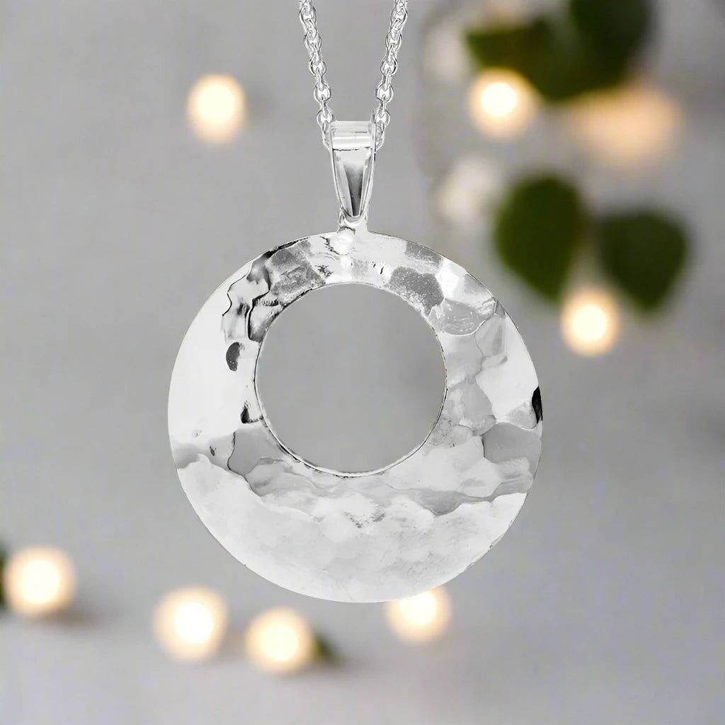 Photo of Open Hammered Circle Necklace in a decorative scene, designed by , available at Plumb Gold & Plumb Silver