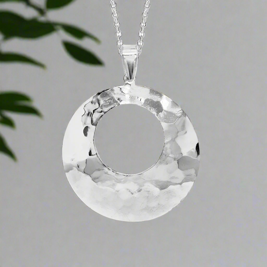 Photo of Open Hammered Circle Necklace in a decorative scene, designed by , available at Plumb Gold & Plumb Silver