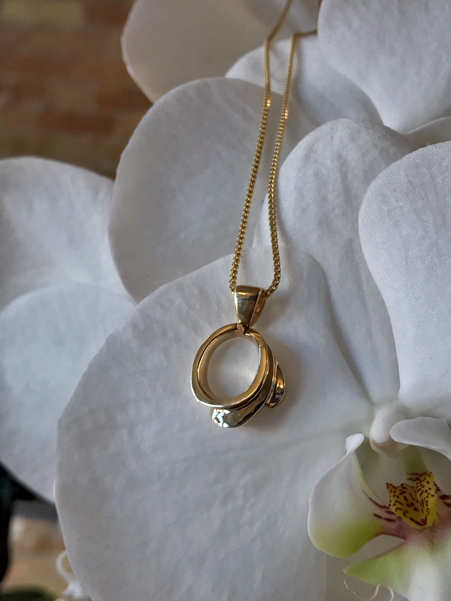 Photo of Open Swirl Pendant in a decorative scene, designed by , available at Plumb Gold & Plumb Silver