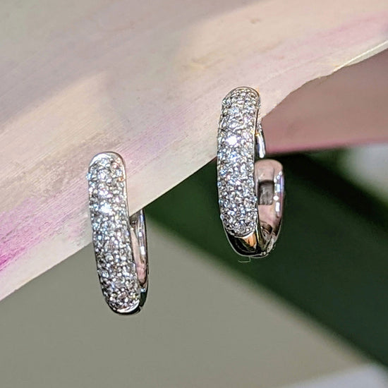 Photo of Pave hinged huggie hoops in a decorative scene, designed by , available at Plumb Gold & Plumb Silver