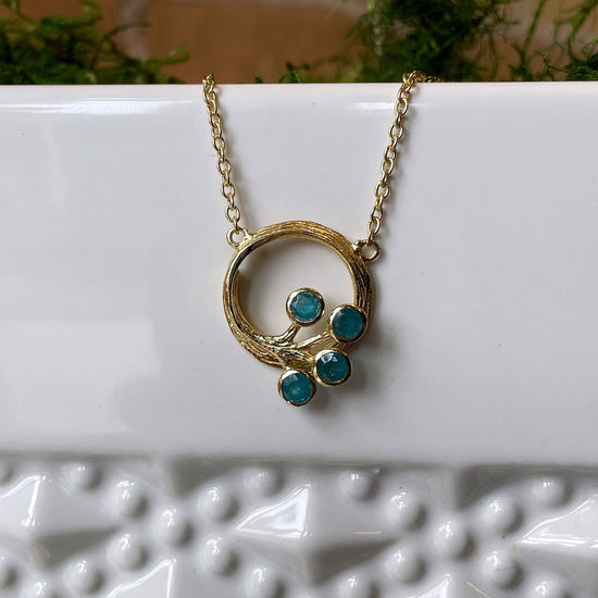 Photo of “Peacock” Apatite Necklace in a decorative scene, designed by , available at Plumb Gold & Plumb Silver