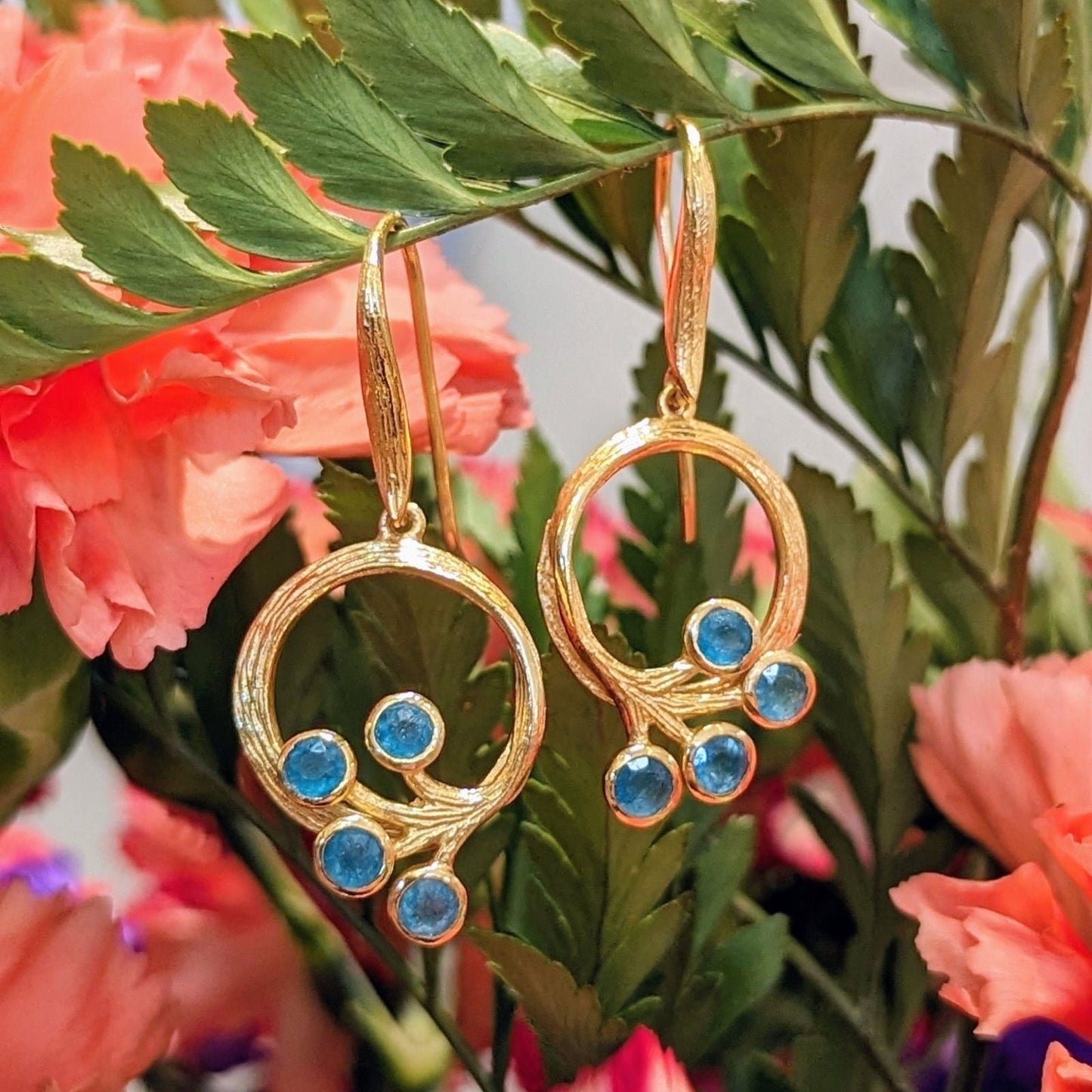 Photo of Peacock Earring in a decorative scene, designed by , available at Plumb Gold & Plumb Silver