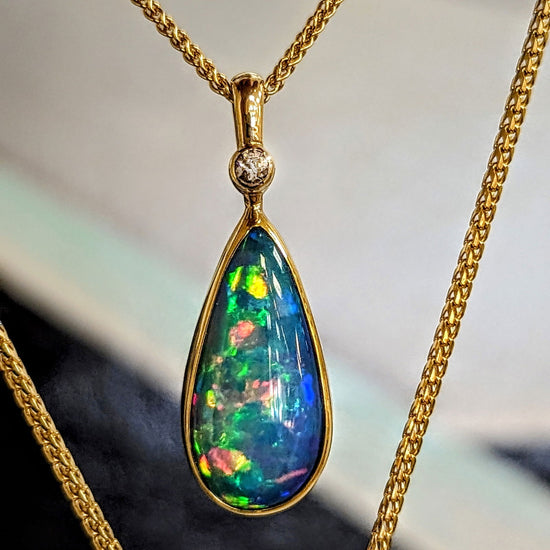 Photo of Pear Drop Opal Pendant in a decorative scene, designed by , available at Plumb Gold & Plumb Silver