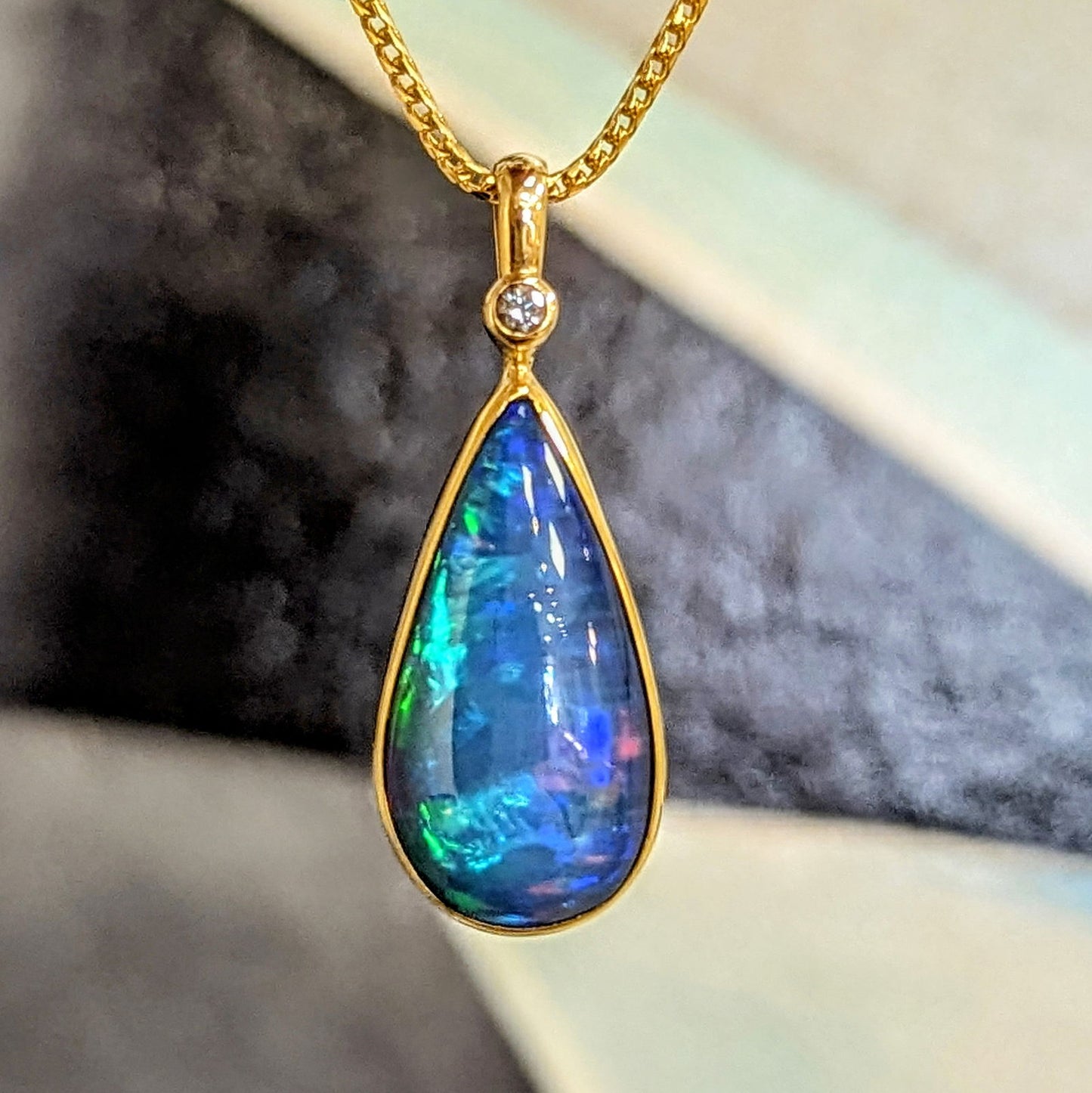 Photo of Pear Drop Opal Pendant in a decorative scene, designed by , available at Plumb Gold & Plumb Silver