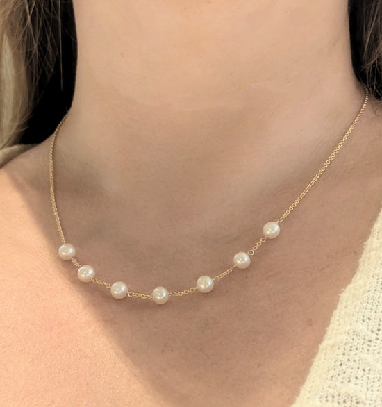 Photo of Pearl Station Necklace in a decorative scene, designed by , available at Plumb Gold & Plumb Silver