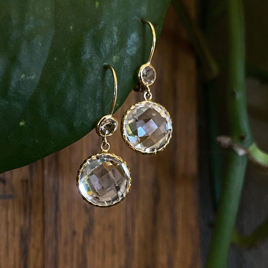 Photo of Petite Crystal Quartz Dangle Earrings in a decorative scene, designed by , available at Plumb Gold & Plumb Silver