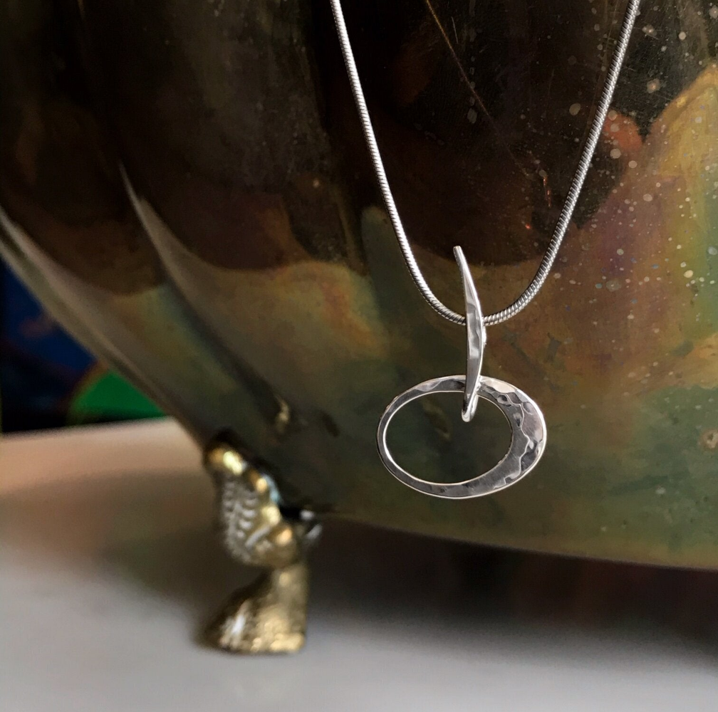 Photo of "Petite Elliptical" Necklace in a decorative scene, designed by , available at Plumb Gold & Plumb Silver