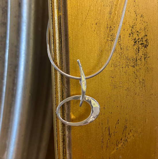 Photo of "Petite Elliptical" Necklace in a decorative scene, designed by , available at Plumb Gold & Plumb Silver