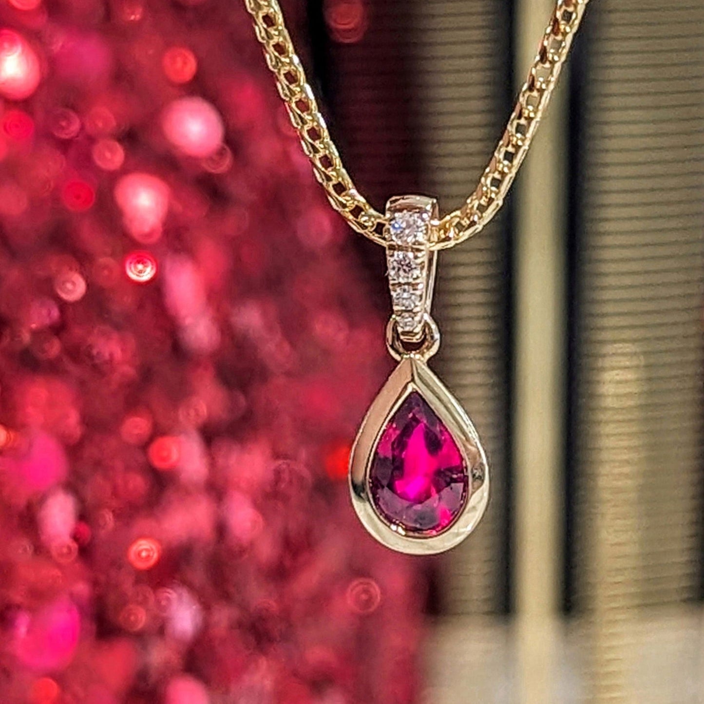 Photo of Petite Ruby and Diamond Pendant in a decorative scene, designed by , available at Plumb Gold & Plumb Silver