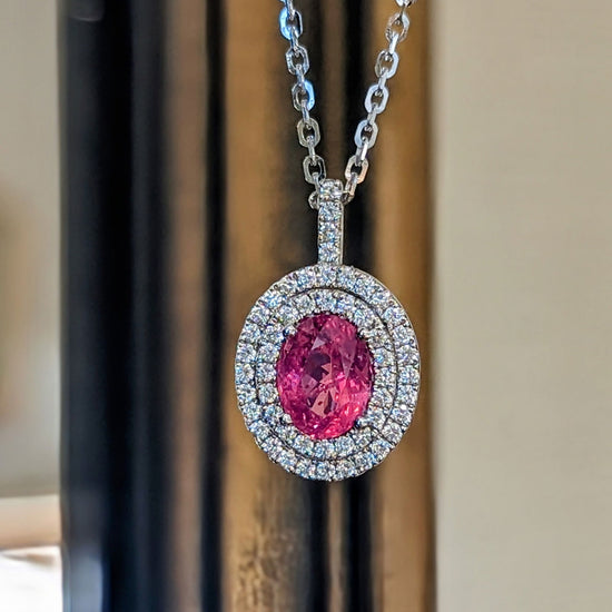Photo of Pink Sapphire Double Halo Pendant in a decorative scene, designed by , available at Plumb Gold & Plumb Silver