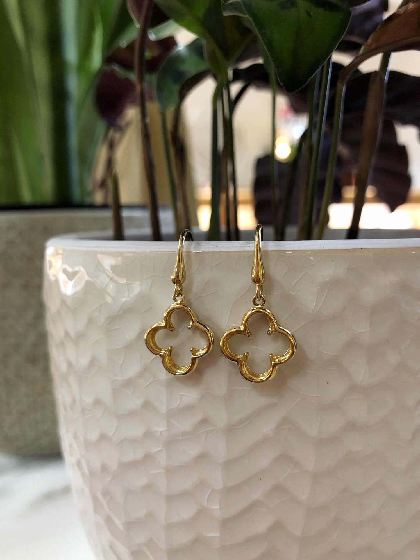 Photo of Quatrefoil Dangle Earrings in a decorative scene, designed by , available at Plumb Gold & Plumb Silver