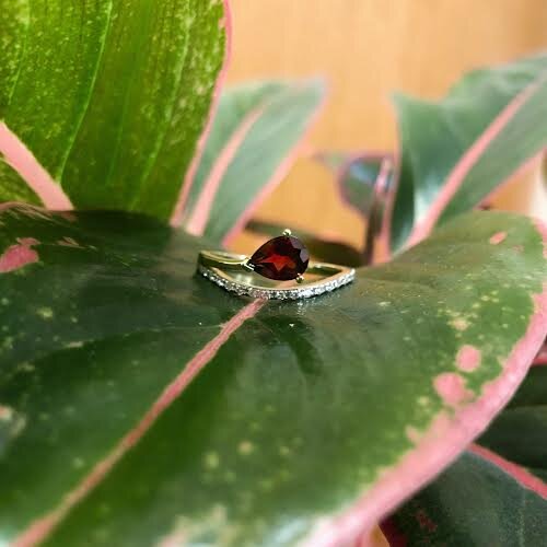 Photo of Red Garnet Swoop Ring in a decorative scene, designed by , available at Plumb Gold & Plumb Silver