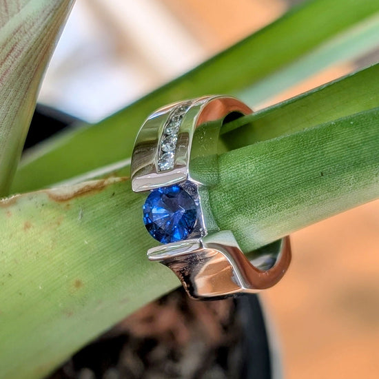 Photo of "Roxanne" Sapphire Ring in a decorative scene, designed by , available at Plumb Gold & Plumb Silver