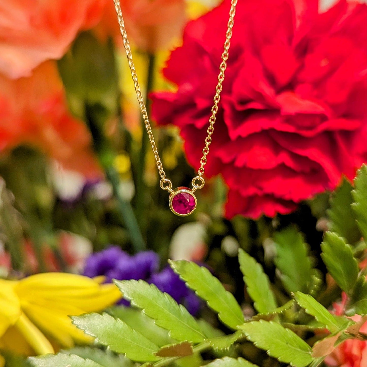 Photo of Ruby Bezel Necklace in a decorative scene, designed by , available at Plumb Gold & Plumb Silver