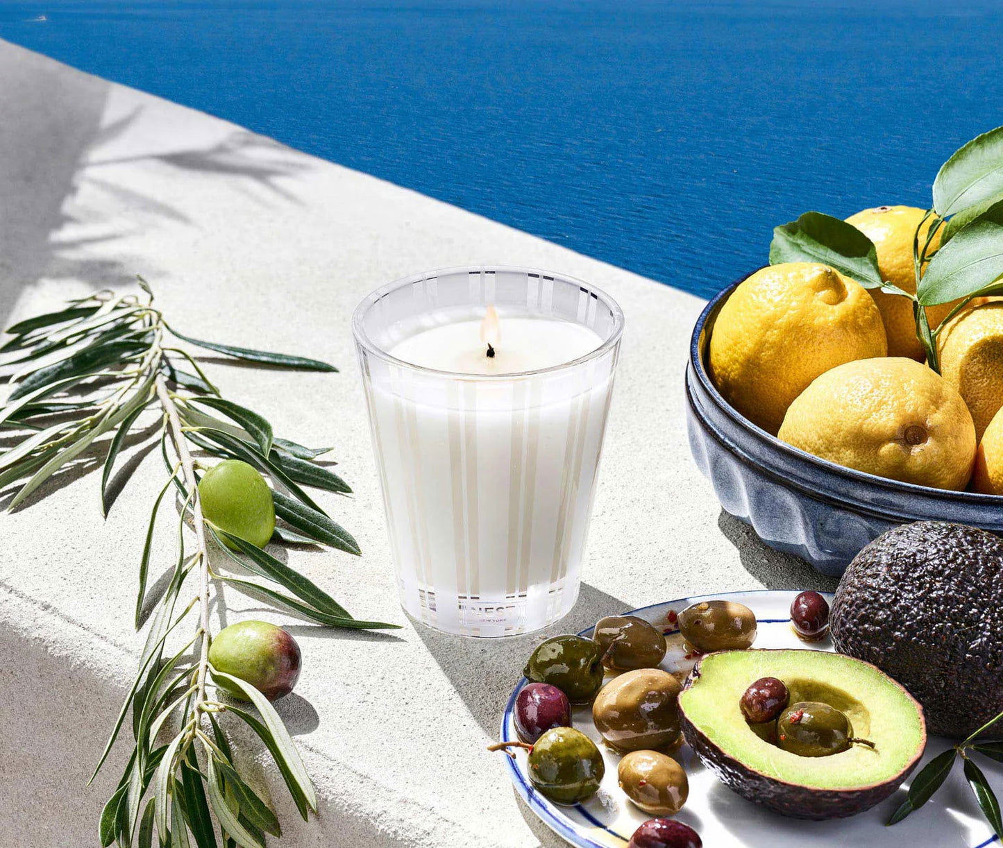 Photo of Santorini Olive and Citron Candle in a decorative scene, designed by , available at Plumb Gold & Plumb Silver