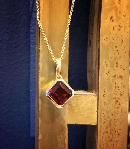 Photo of Square Gemstone Pendant in a decorative scene, designed by , available at Plumb Gold & Plumb Silver
