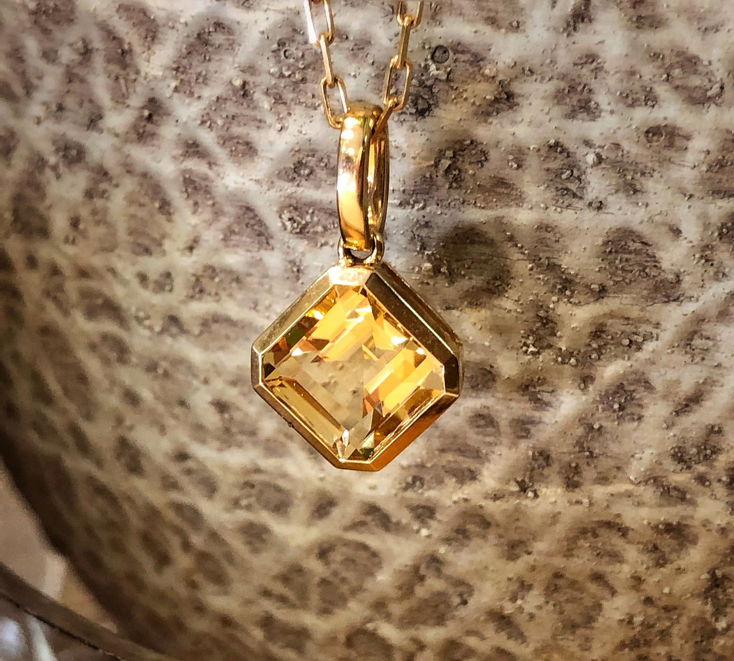 Photo of Square Gemstone Pendant in a decorative scene, designed by , available at Plumb Gold & Plumb Silver
