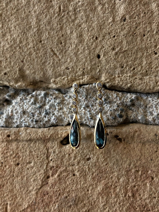 Photo of Stanton Color London Blue Topaz and Diamond Dangles in a decorative scene, designed by , available at Plumb Gold & Plumb Silver