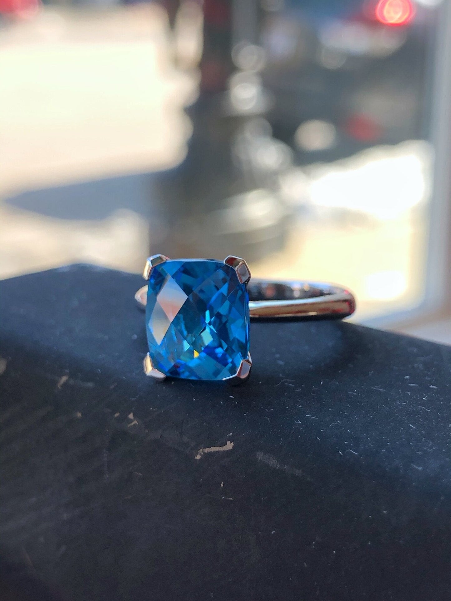 Photo of Stanton Color Rectangle Cushion Blue Topaz Ring in a decorative scene, designed by , available at Plumb Gold & Plumb Silver